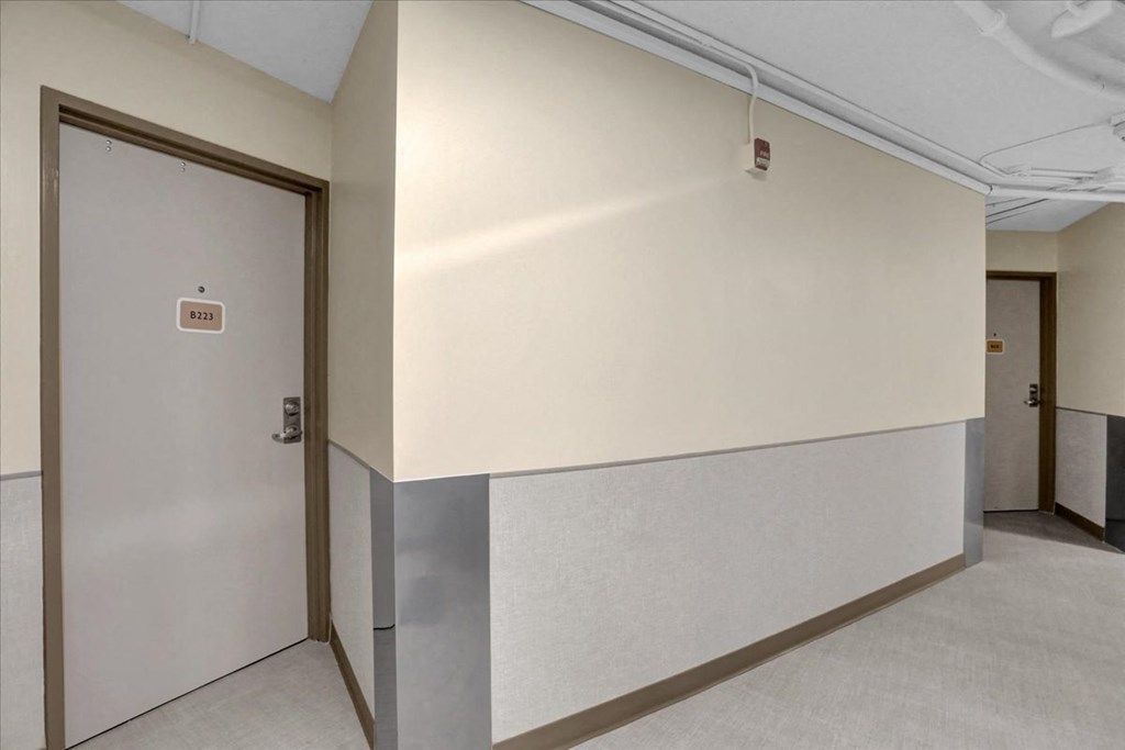 the hallway of a building with a door and a white wall