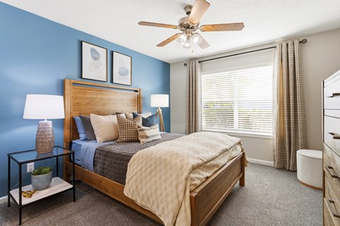 A bedroom with a bed, nightstand, and a ceiling fan.