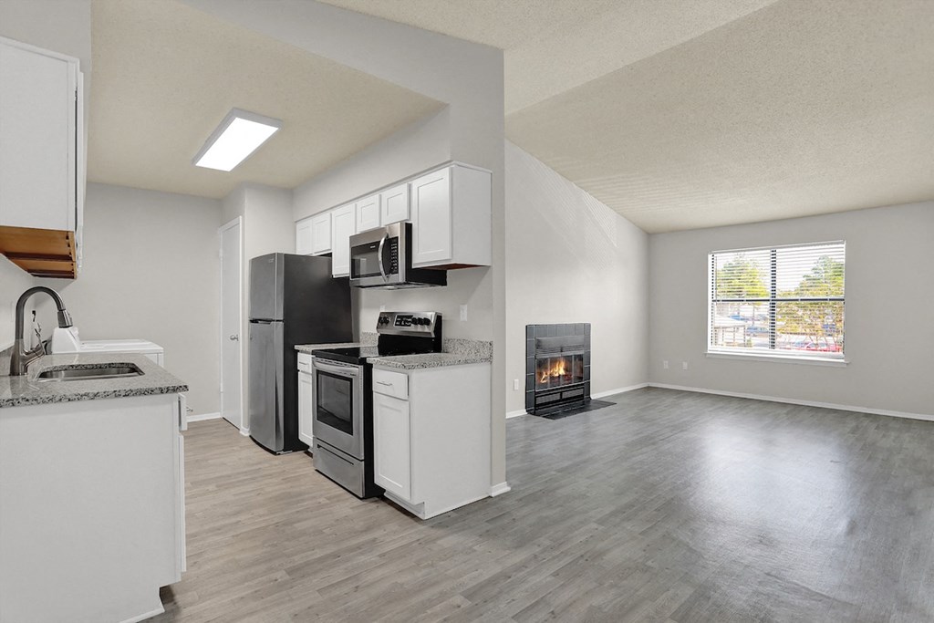 a large open living room with a vaulted ceiling and a renovated kitchen at Rock Creek Apartments