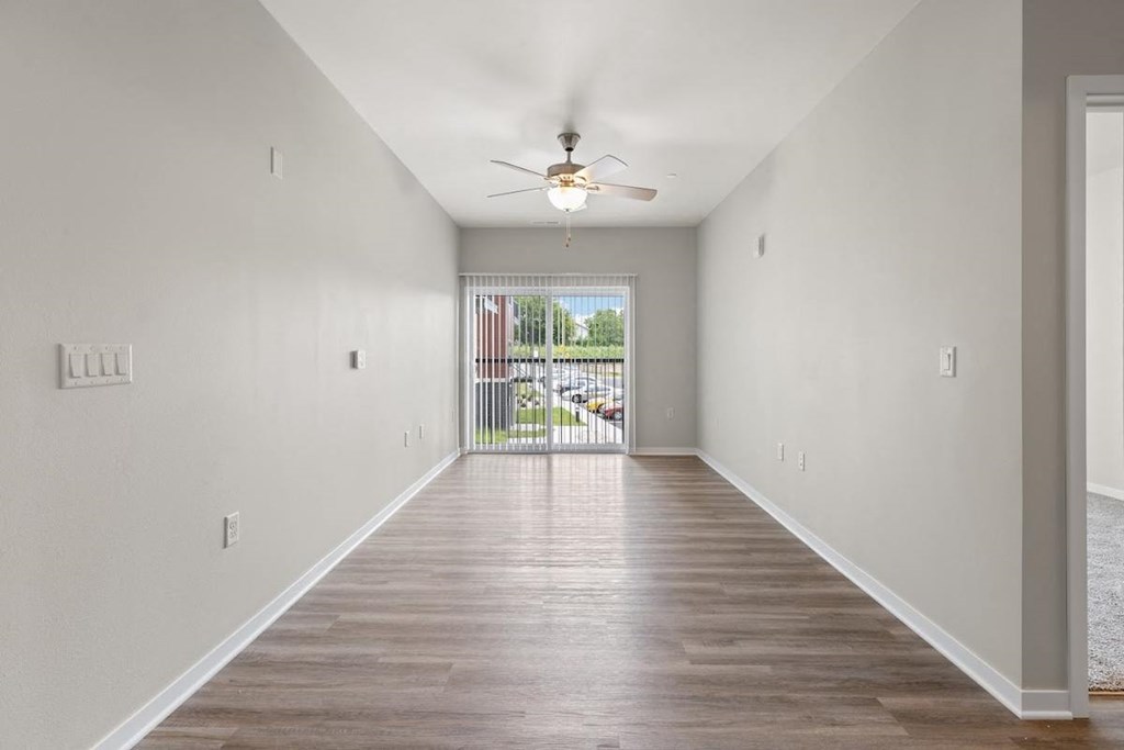 a large living room with wood-style flooring, a ceiling fan, and a large window
