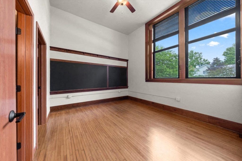 a bedroom with a ceiling fan, large windows, and chalkboard in a Spartan Lofts apartment home