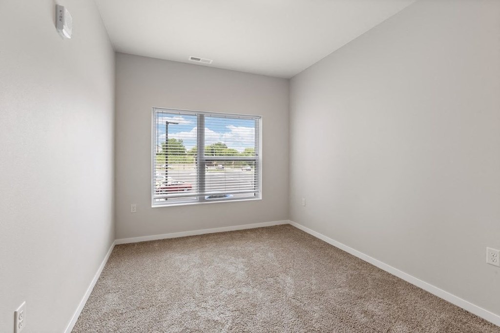 a bedroom with a large window filled with natural light in a home at River Flats Apartments