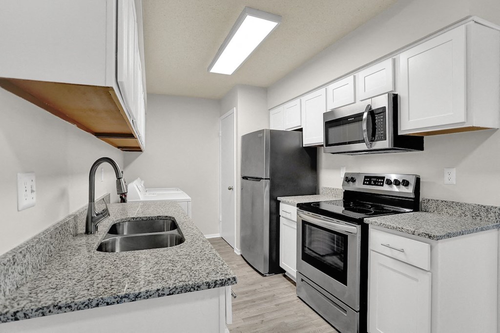 a renovated kitchen with stainless steel appliances, granite coutnertops, and white cabinets at Rock Creek