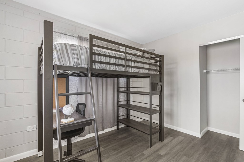 A room with a bunk bed and a desk.