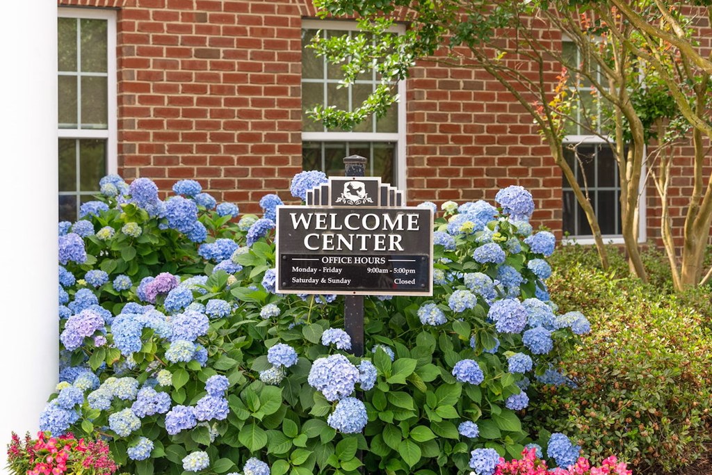 welcome center sign surrounded by blue hydrangea in front of Fenwyck Manor Clubhouse