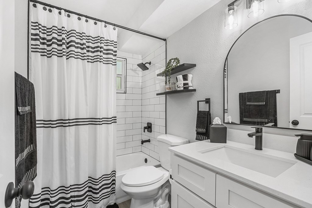 A white bathroom with a black and white shower curtain.