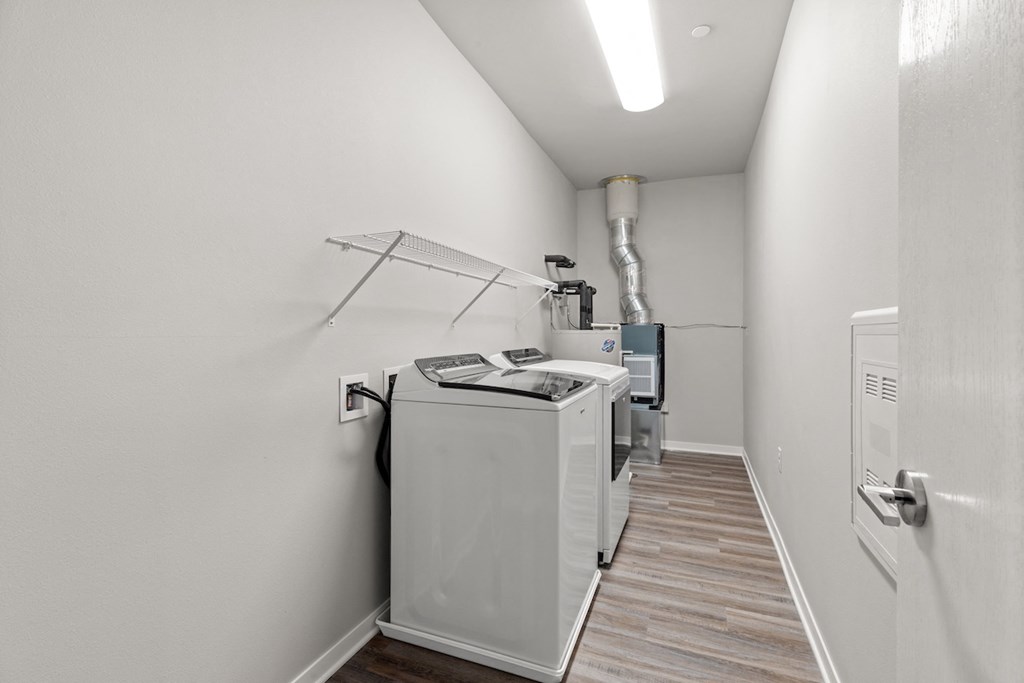 an in-home laundry room with a washer, dryer, and built-in shelving