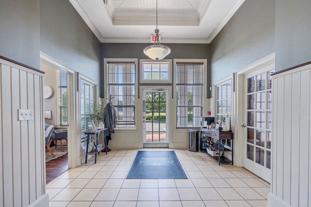 The Centerville Manor lobby with a blue rug and a door that has an exit sign on it