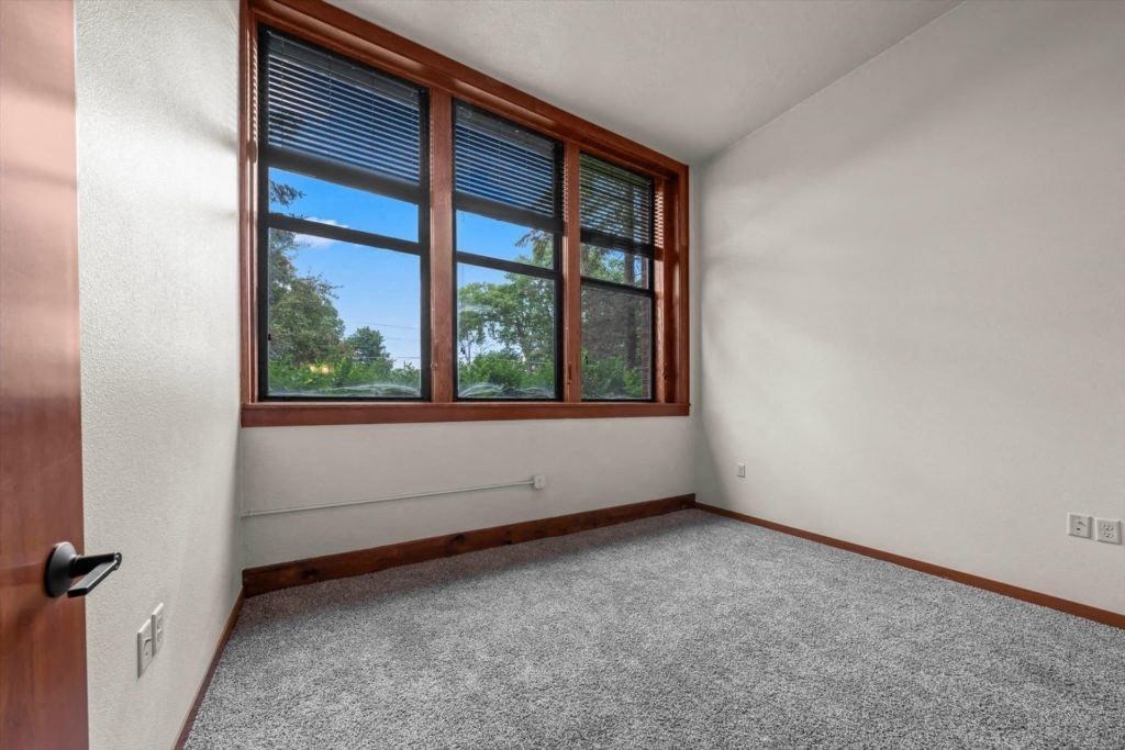 a bedroom with large windows and plush carpet in an apartment at Spartan Lofts