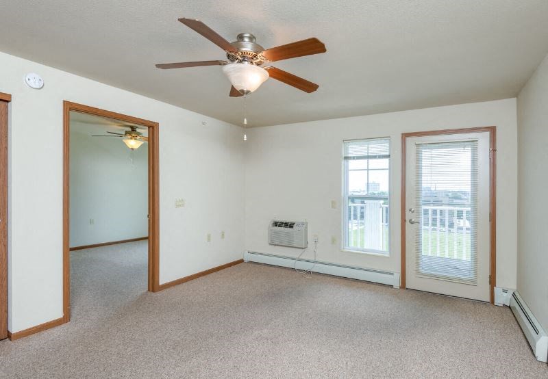 living room in a  Harborside Commons residence with ceiling fan, AC, and large windows