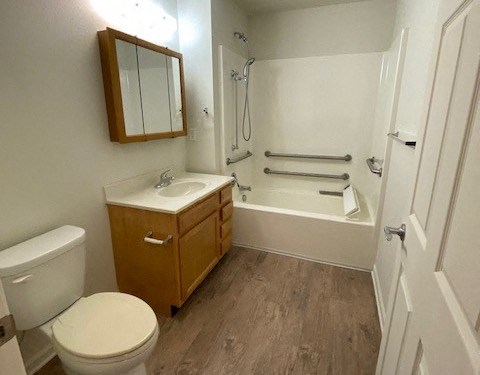 bathroom with toilet, sink, and bathtub with handrails