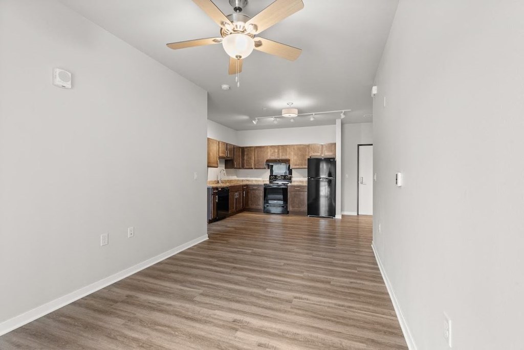 an open and airy living room and kitchen with a ceiling fan and overhead lighting