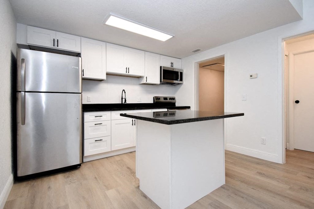 a kitchen with white cabinets and a stainless steel refrigerator