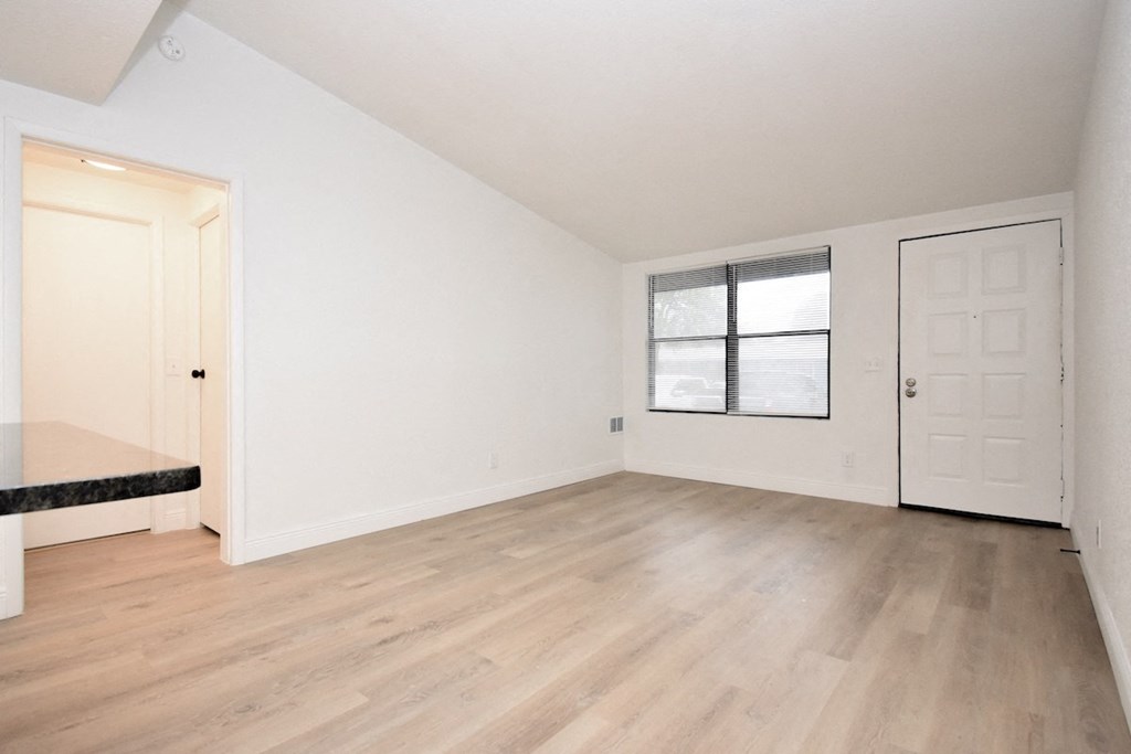 an empty living room with white walls and a window