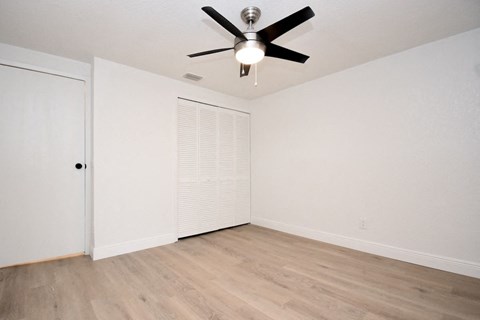 an empty living room with white walls and a ceiling fan