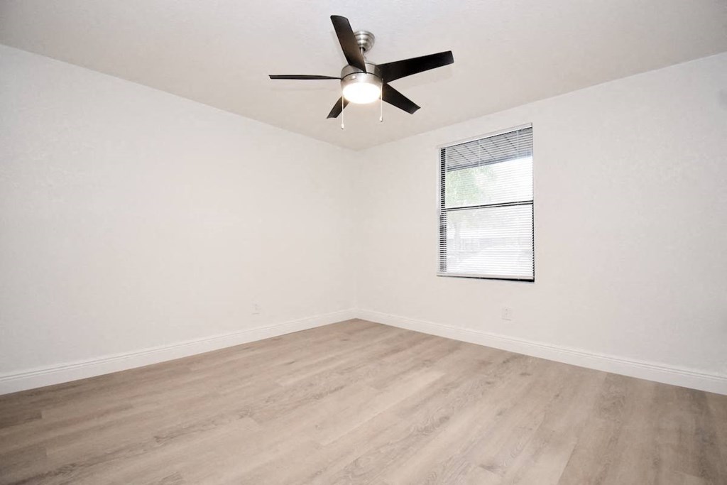 an empty living room with wood floors and a ceiling fan