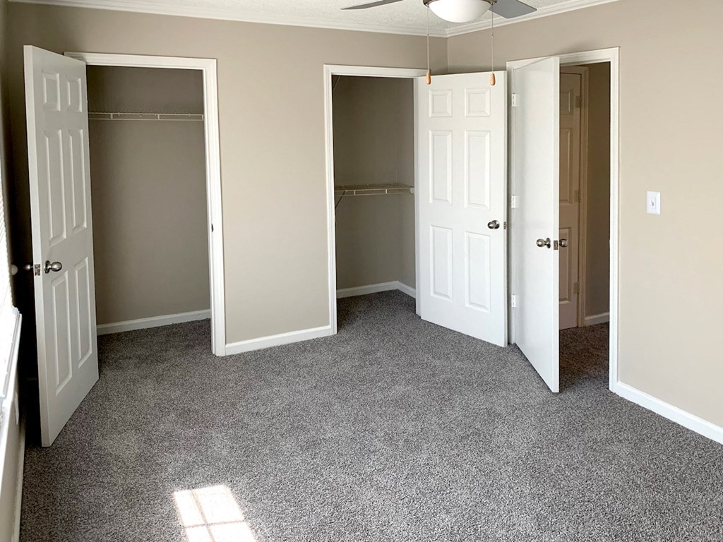 double closet and bathroom in master bedroom with ceiling fan