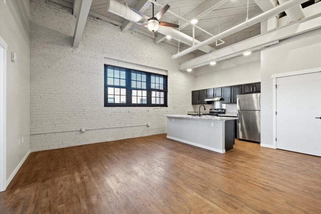 a large loft with wood floors, exposed ductwork, and a modern kitchen with stainless steel appliances