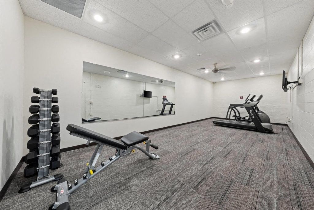 free weights and a weight bench with cardio equipment at Spartan Lofts