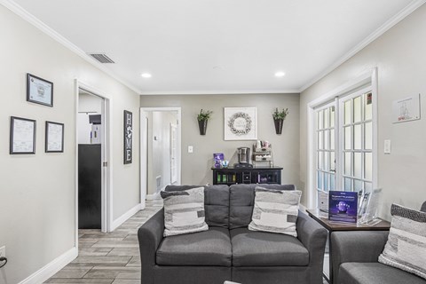 A living room with a grey couch and a black fridge.