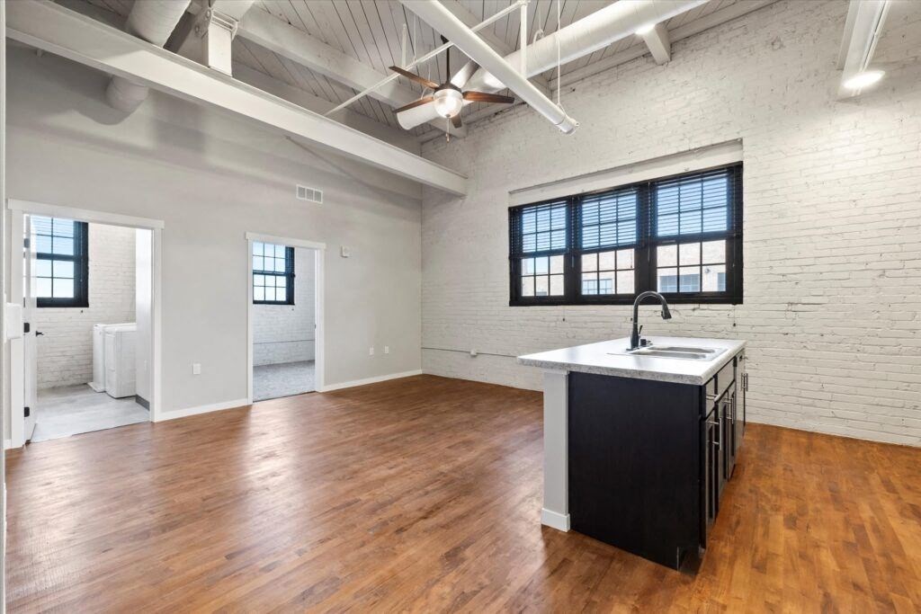 an open living room with a kitchen and exposed ductwork at Brooke Street Lofts