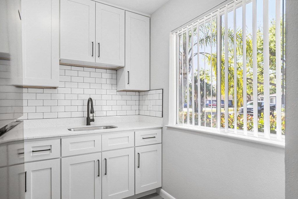 A kitchen with white cabinets and a white sink.