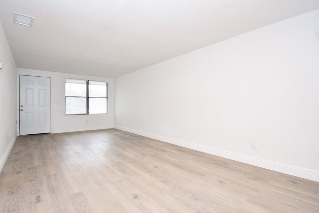 an empty living room with white walls and wood-style floors