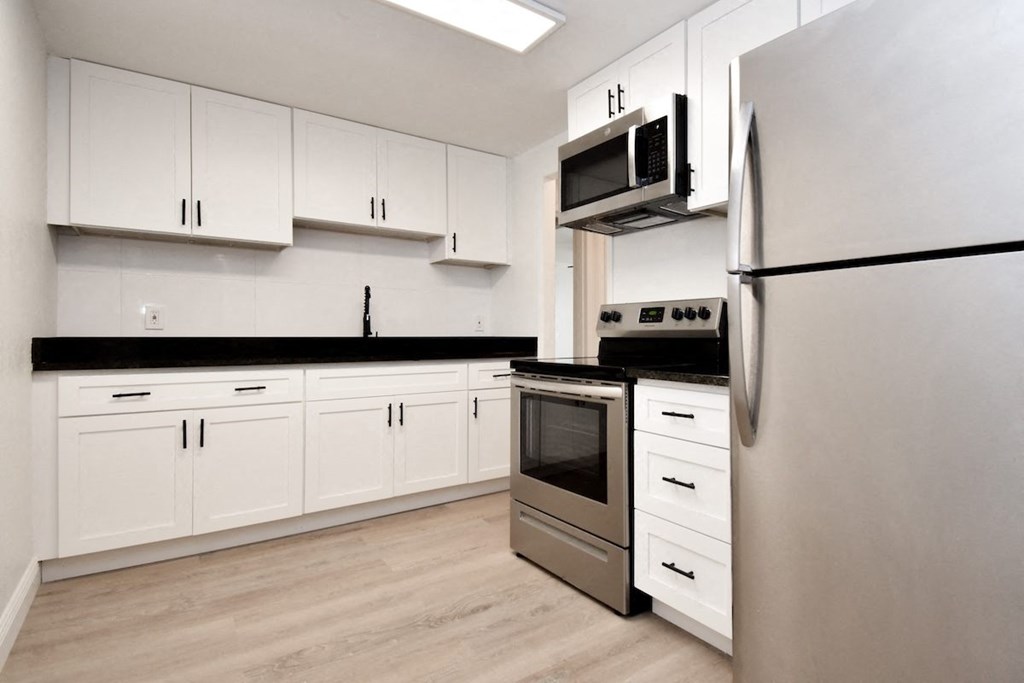 a white kitchen with stainless steel appliances and white cabinets