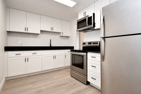 a white kitchen with stainless steel appliances and white cabinets