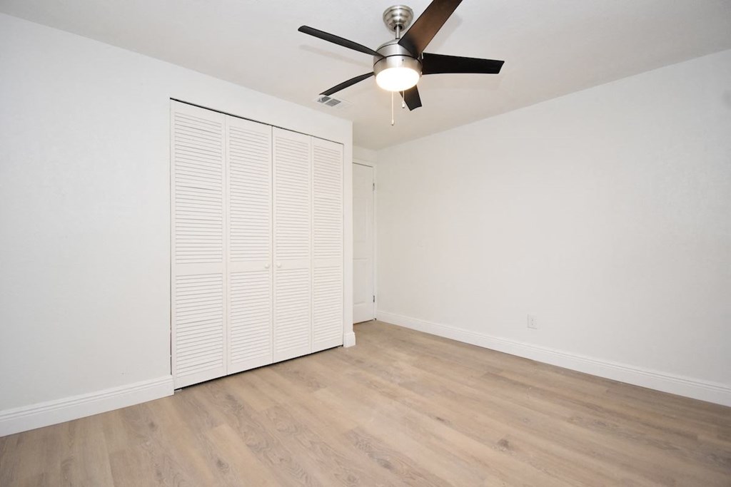 an empty room with a ceiling fan and a closet