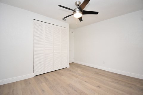 an empty room with a ceiling fan and a closet