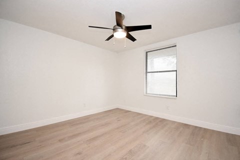 bedroom with illuminated ceiling fan, window, and wood-style flooring
