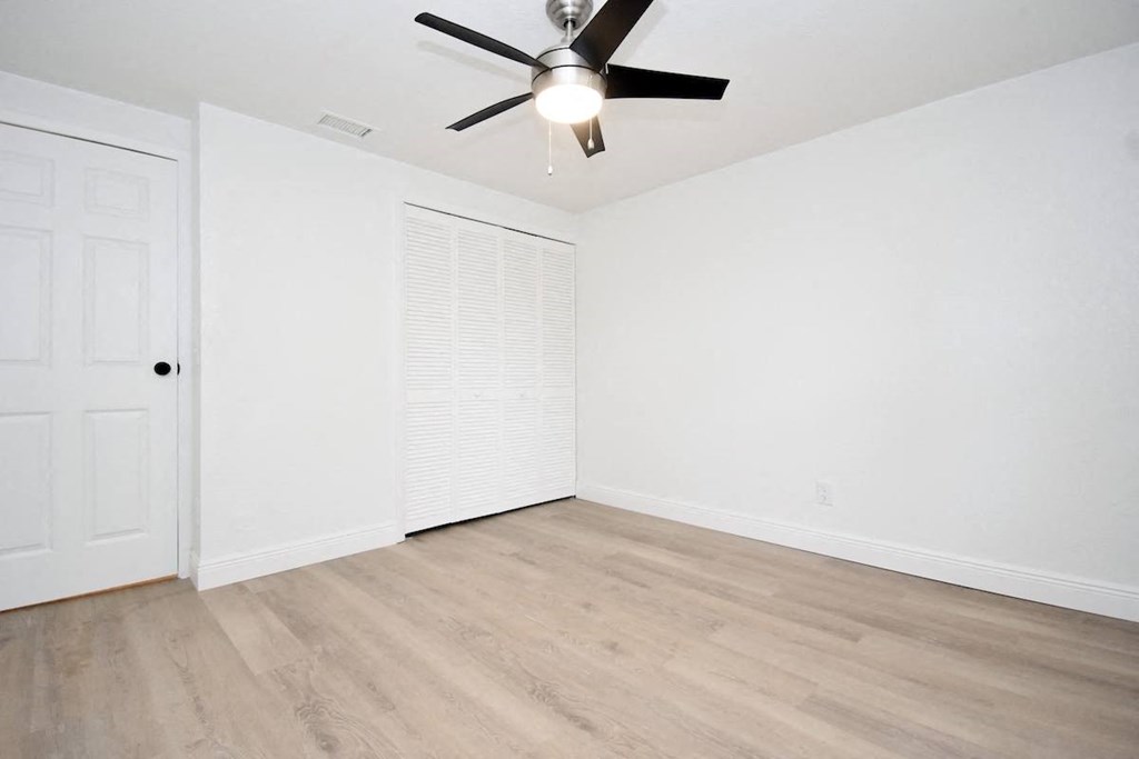 an empty living room with white walls and a ceiling fan