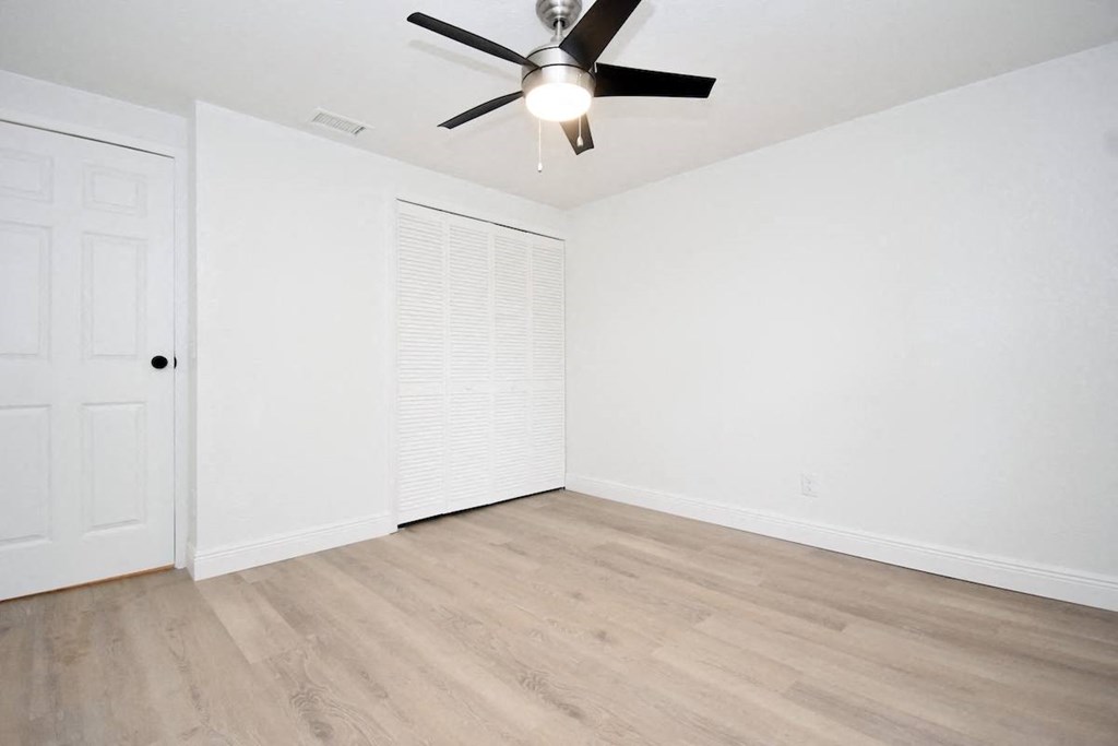 an empty living room with white walls and a ceiling fan