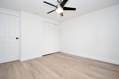 an empty living room with white walls and a ceiling fan