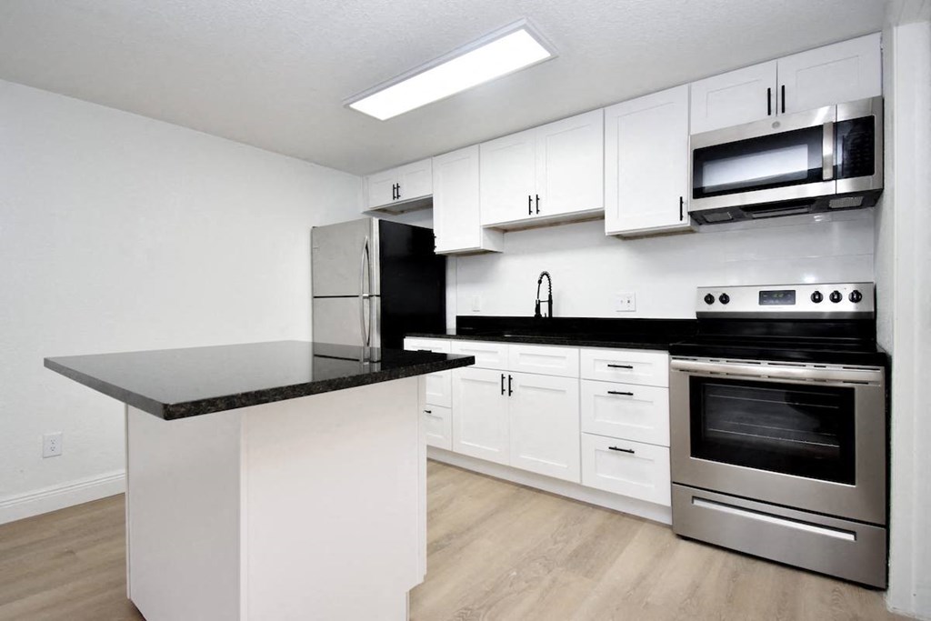 a kitchen with white cabinets and stainless steel appliances