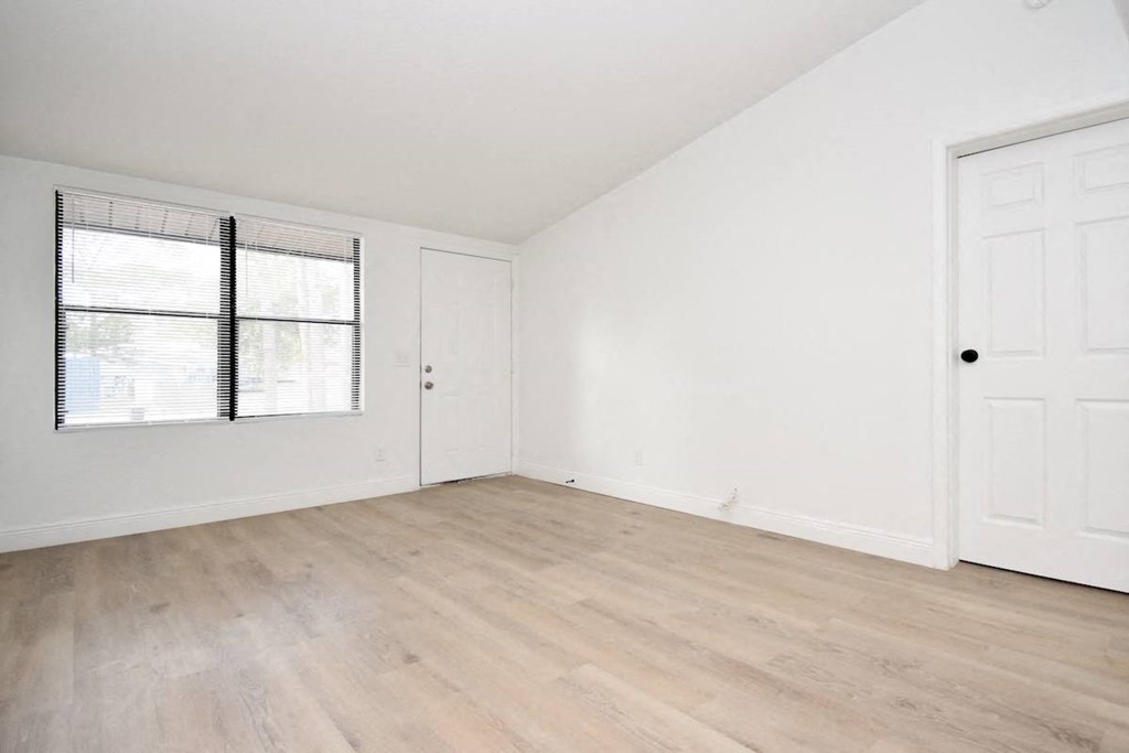 an empty bedroom with white walls and wood floors