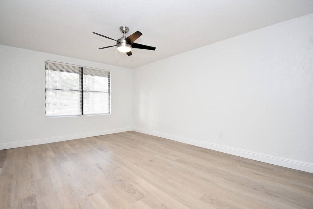 an empty living room with white walls and a ceiling fan