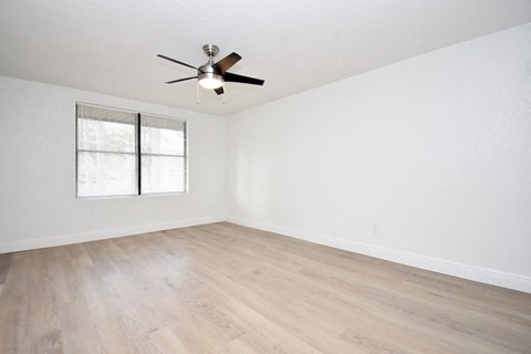an empty living room with white walls and a ceiling fan