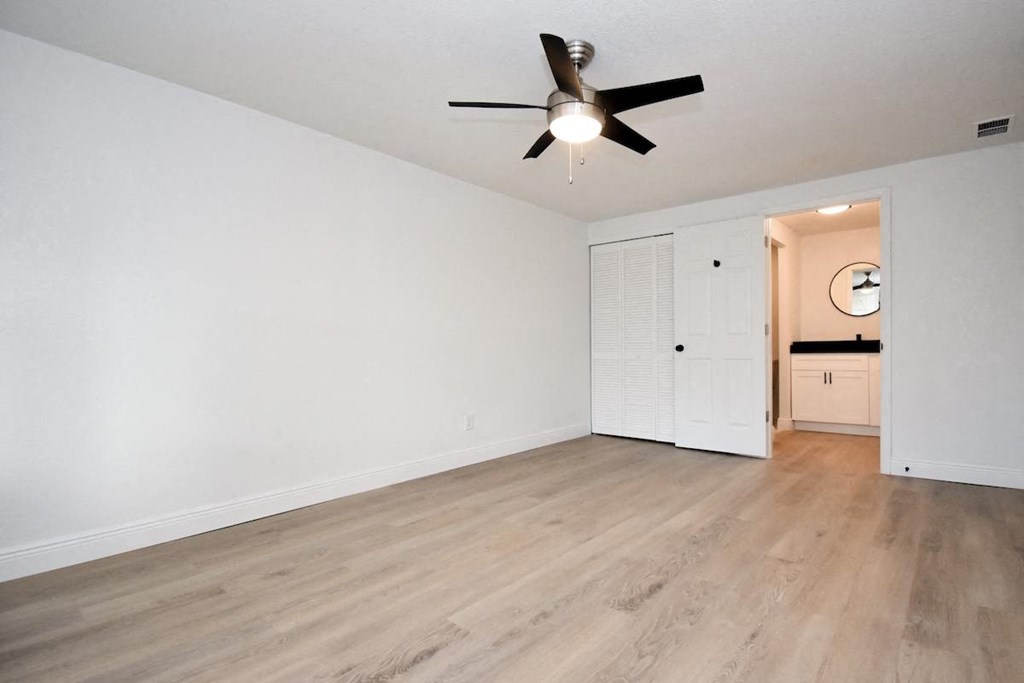 an empty living room with white walls and a ceiling fan