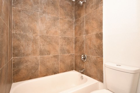 a tiled bathroom with a tub and a toilet