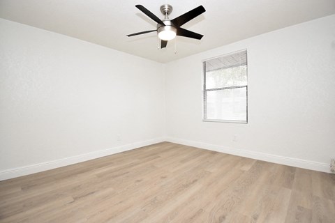 a bedroom with a window and a ceiling fan with a light