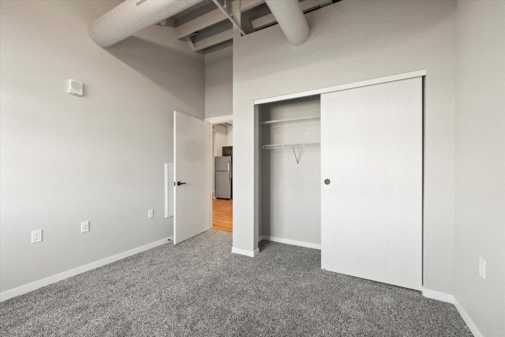 a bedroom with a closet and a carpeted floor at Brook Street Lofts