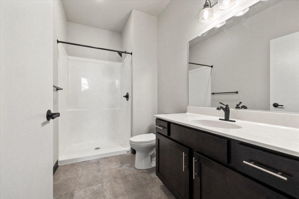 Brooke Street Lofts bathroom with a large sink vanity, toilet, and shower