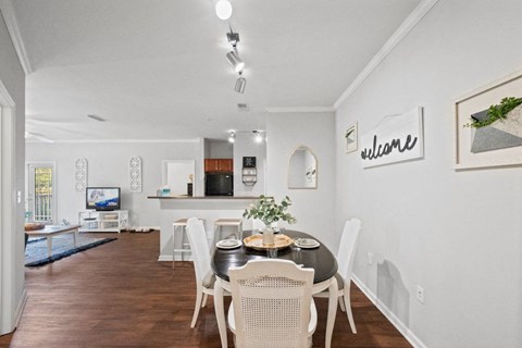 a dining area with a table and chairs and a kitchen in the background