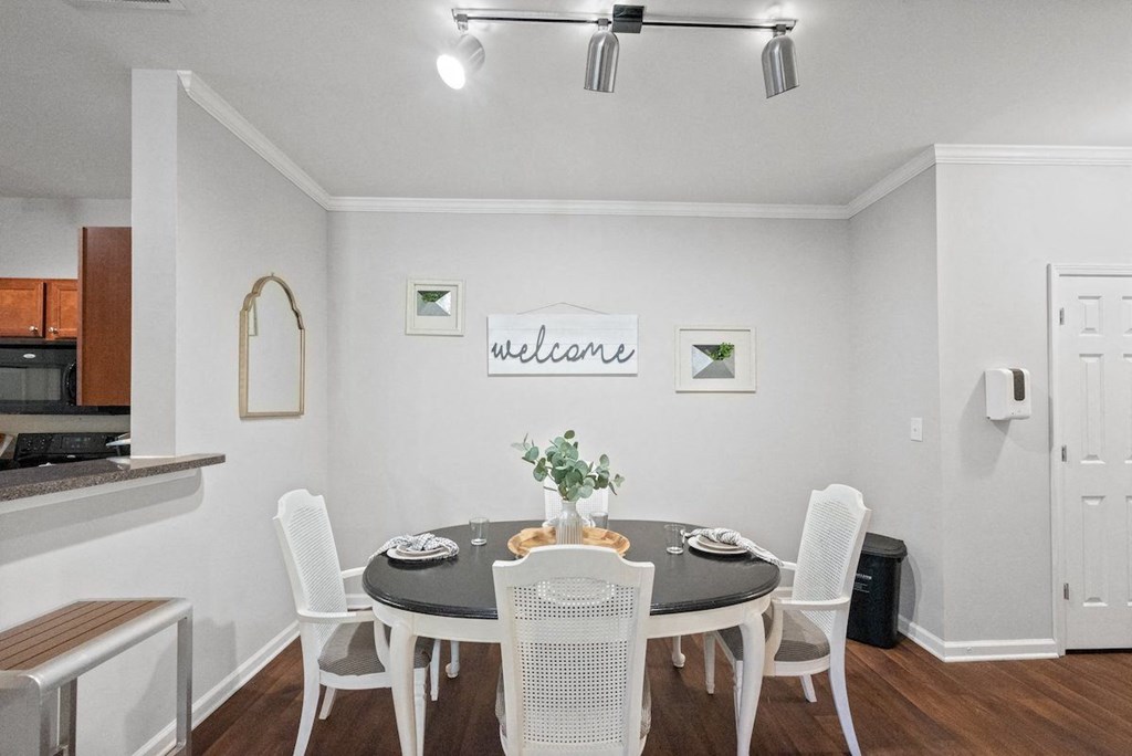 a dining room with a table and chairs and a kitchen in the background