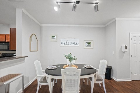 a dining room with a table and chairs and a kitchen in the background