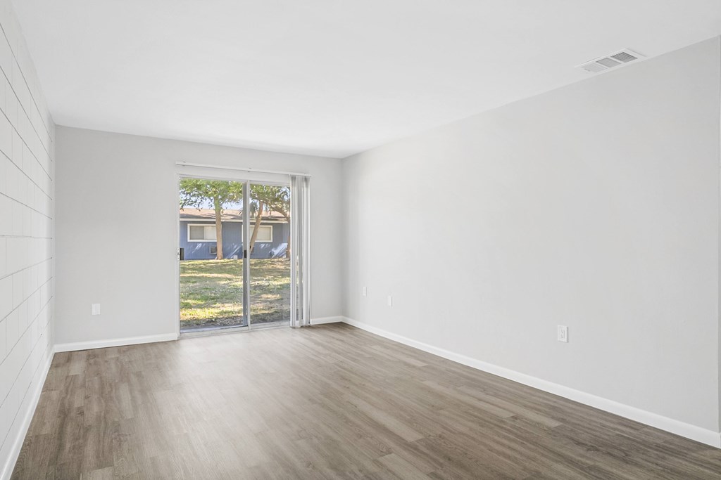 A room with a sliding glass door leading to a backyard.