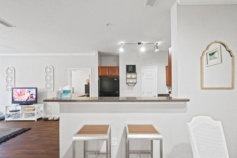 a kitchen and living room with white walls and wood-style floors