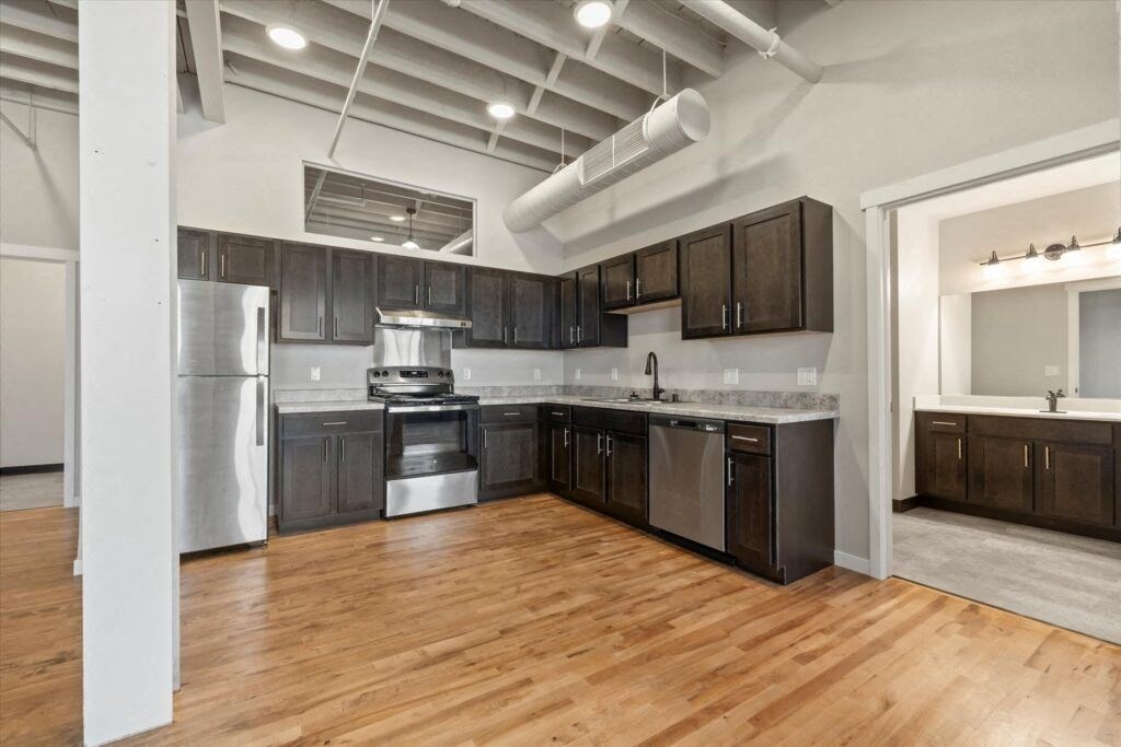 a modern kitchen with stainless steel appliances, high ceilings, and dark wood cabinetry
